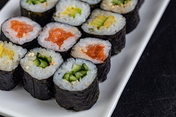 Sushi with fish, with cucumber, with eel, with avocado. Wrapped in Nori Seaweed. Food for vegetarians. Soy sauce, ginger, wasabi in white bowls. Copy space.