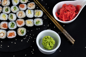Sushi with fish, with cucumber, with eel, with avocado. Wrapped in Nori Seaweed. Food for vegetarians. Soy sauce, ginger, wasabi in white bowls. Copy space.
