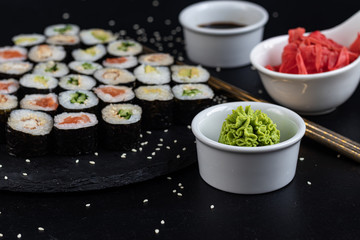Sushi with fish, with cucumber, with eel, with avocado. Wrapped in Nori Seaweed. Food for vegetarians. Soy sauce, ginger, wasabi in white bowls. Copy space.