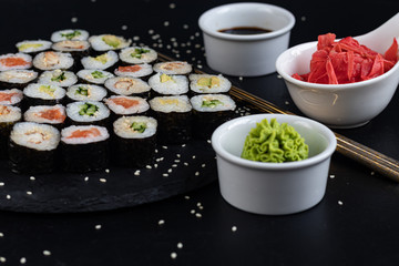 Sushi with fish, with cucumber, with eel, with avocado. Wrapped in Nori Seaweed. Food for vegetarians. Soy sauce, ginger, wasabi in white bowls. Copy space.
