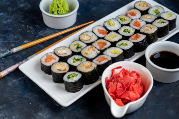 Sushi with fish, with cucumber, with eel, with avocado. Wrapped in Nori Seaweed. Food for vegetarians. Soy sauce, ginger, wasabi in white bowls. Copy space.