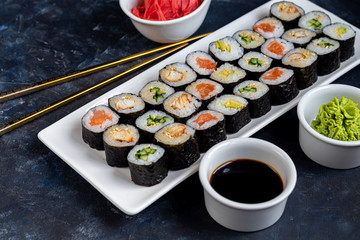 Sushi with fish, with cucumber, with eel, with avocado. Wrapped in Nori Seaweed. Food for vegetarians. Soy sauce, ginger, wasabi in white bowls. Copy space.