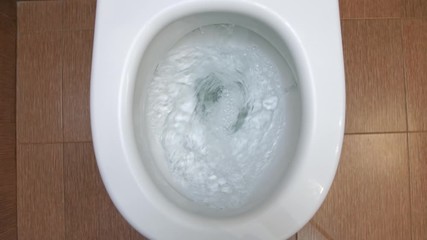 Water flushes the white toilet