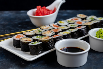 Sushi with fish, with cucumber, with eel, with avocado. Wrapped in Nori Seaweed. Food for vegetarians. Soy sauce, ginger, wasabi in white bowls. Copy space.