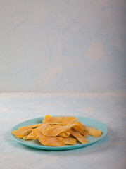 Natural mango chips on a blue plate on a light background. Vertically