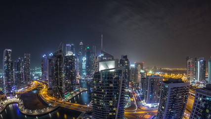 Obraz premium Aerial view of Dubai Marina residential and office skyscrapers with waterfront night timelapse