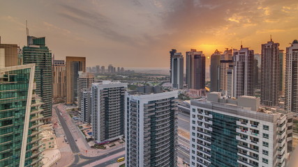 Fototapeta na wymiar Sunrise view of various skyscrapers and towers in Dubai Marina from above aerial timelapse