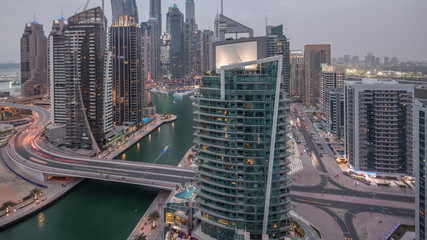 Obraz premium Aerial view of Dubai Marina residential and office skyscrapers with waterfront day to night timelapse