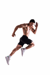 Muscle male model in black sports shorts and white sneakers in a jumping pose on white background. Sports motion concept. Studio shot.