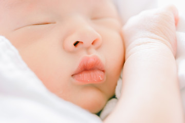 tender lips and nose of a newborn baby asleep on a diaper