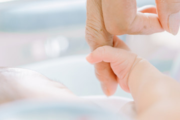 Newborn Baby is holding fingers of his grandmother - happy family moments