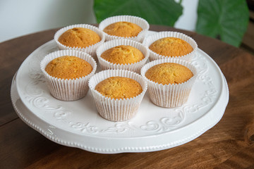 vanilla cupcakes on white plate  on wooden table