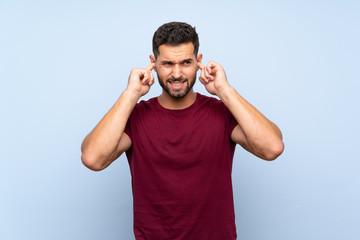 Fototapeta premium Handsome man over isolated blue background frustrated and covering ears