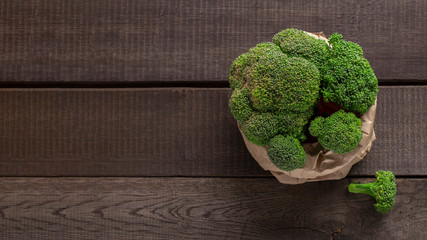 Fresh broccoli in paper bag on wooden background