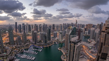 Fototapeta premium Dubai Marina skyscrapers and jumeirah lake towers view from the top aerial night to day timelapse in the United Arab Emirates.