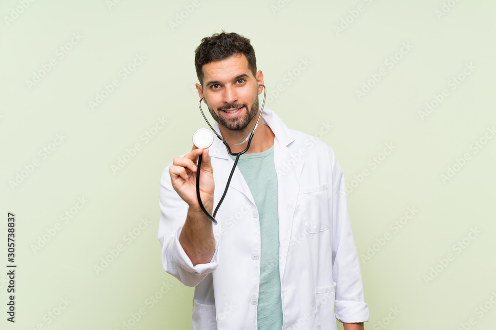 Wall mural Young doctor man over isolated green wall