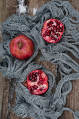 Fresh red  pomegranate in gray scarf on wooden old table