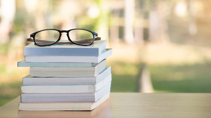 Stack of favorite old books with eyeglasses on natural background,  relax time in holiday concept,...