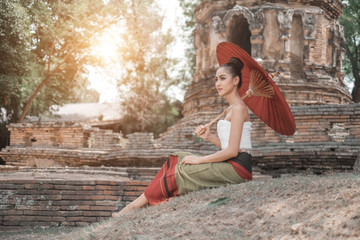 Obraz premium Beautiful Thai women wearing traditional Thai clothes holding ancient red umbrellas in temples Thailand, woman concept
