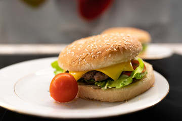 Homemade hamburger with cherry tomato on the plate closeup. Selective focus