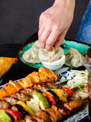 girl eats manti with sour cream in her hands