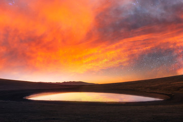 Fototapeta na wymiar Beautiful landsckape. In the small volkanic lake reflected amazing sunset sky with beautiful orange clouds.