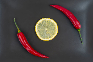 Red hot pepper with lemon on a gray plate. Healthy vegetable food and vitamins