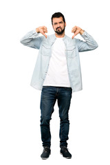 Full-length shot of Handsome man with beard showing thumb down over isolated white background