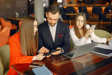 Man and two beautiful women working. People in a cafe. Twins in a elegant suits
