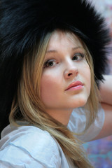 Teen girl looks up. Natural blonde with long hair in a silver fox hat