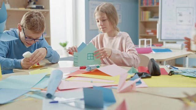 Elementary School Arts & Crafts Class: Diverse Group of Smart Children Have Fun on a Handicraft Project, Using Colorful Paper, Scissors and Glue to Create Fun Papier Mache. Arc Camera Shot