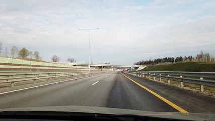 Fototapeta premium The car moves on an asphalt highway. Front view through the windshield.