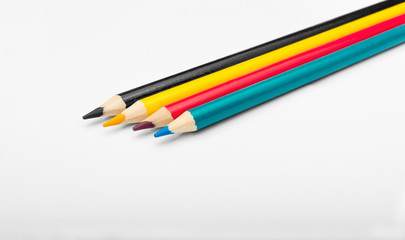 Four colored pencils. The colors cyan, magenta, yellow and black. The concept of polygraphy.