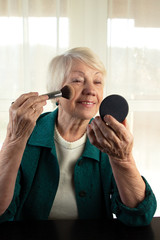 Senior women hold brush and mirror and makeup powder. Beautiful mature lady.