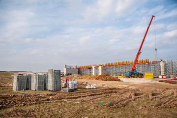 Crane and scaffolding piled on a pallet at the construction of a bridge