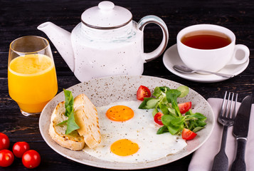 Breakfast of two eggs, served with grenice and tomatoes with orange juice