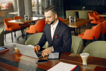 Handsome man in a black suit. Businessman working in a cafe