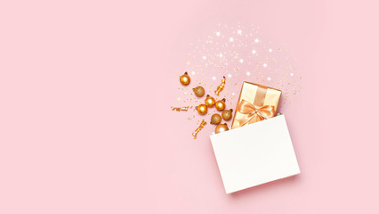 Beautiful golden gift white paper bag confetti stars Christmas balls on pink background top view...