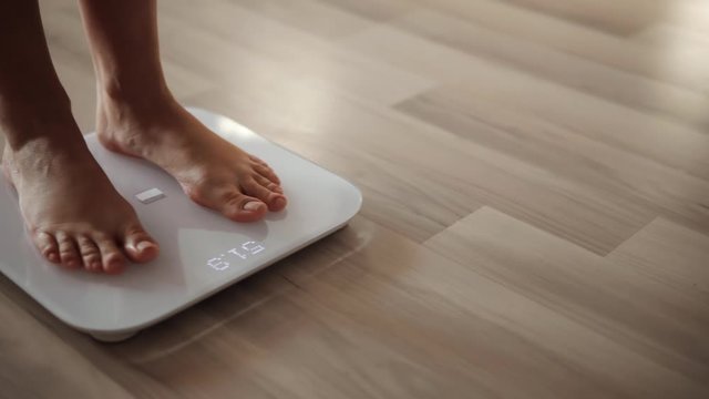 Woman On Scales Measure Weight.Girl Legs On Bathroom Scale.Weighing Scales Checking Body Weight.Human Barefoot Measuring Body Weight Or Overweight.Close Up Woman Legs Checking Body Weight