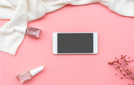 Women cloth, nail polish and mobile phone on pink background, beauty concept, top view, copy space.