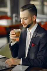 Handsome man in a black suit. Businessman working in a cafe