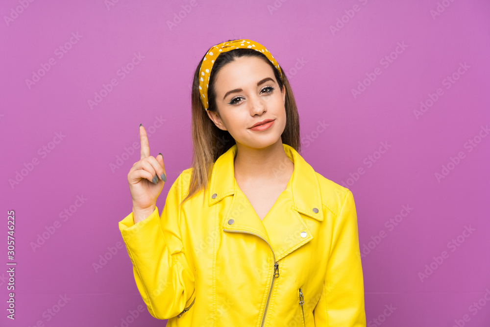 Wall mural Young woman over purple background pointing with the index finger a great idea