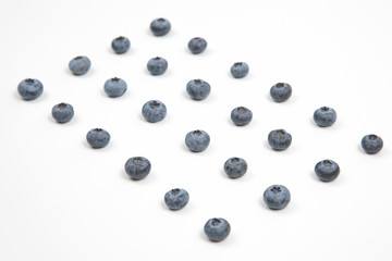 blueberries are laid out in rows on a white background