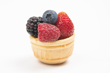 blueberries, raspberries, strawberries and blackberries in a waffle basket on a white background