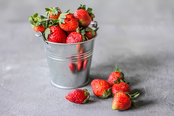 Photo of heap of fresh strawberries in the bowl on rustic grey background..A bunch of ripe strawberries in a can bowl on the table. Copy space. Healthy fresh fruit. Organic food. Clear food