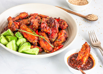 Baked Chicken Wing in a Dip Bowl with Hot Sauce,  Chicken WIngs in a Bowl in the Background, Chicken Appetizer Photo.