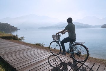 Fototapeta premium young men riding a bicycle on bike trail at the lake in the morning. Active people. Outdoors