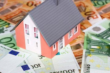 Model house with (euro)banknotes as a concept photo for high real estate prices