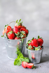 Photo of heap of fresh strawberries in the bowl on rustic grey background..A bunch of ripe strawberries in a can bowl on the table. Copy space. Healthy fresh fruit. Organic food. Clear food