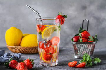 Photo of refreshing summer iced cold drink with strawberry lemon lemonade in glass. Mineral water with fresh strawberries lemon with a grey background. Detox water with strawberry lemon. Copy space.